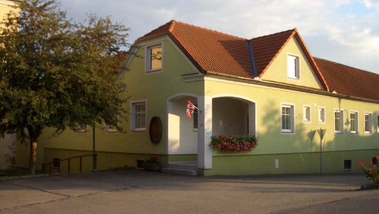 Gästezimmer Eingang, © Kurt Englmayer Gelbes Gebäude mit rotem Dach und Blumen am Eingang.