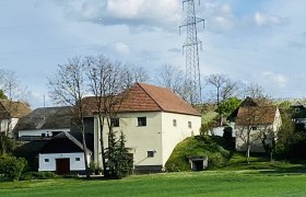 Früher war das ein beliebter Weideplatz, © Weinstraße Weinviertel Ländliche Szene mit Häusern und Strommast im Weinviertel.