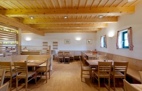 Weingut & Buschenschank Greilinger, © Greilinger Innenansicht eines gemütlichen Gastraums mit Holzmöbeln und Holzbalkendecke.