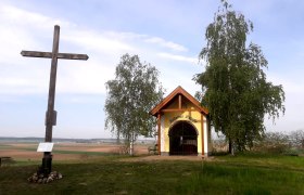 Kraftplatz St. Peter am Stein, © Robert Appoyer Ein Holzkreuz und eine kleine Kapelle auf einem Hügel mit Bäumen und weitem Blick über die Landschaft.