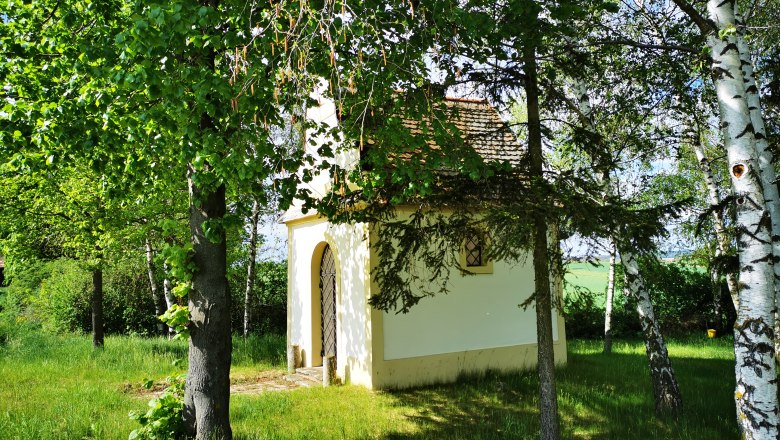 Hubertuskapelle Pernersdorf, © Weinstraße Weinviertel Kleine Kapelle umgeben von Bäumen und Wiese bei Sonnenschein.