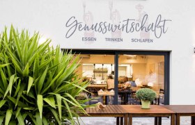 Schönes Ambiente drinnen und draußen, © Genusswirtschaft Außenansicht eines Restaurants mit der Aufschrift 'Genusswirtschaft'.