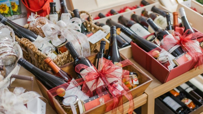 Wein & Genuss Geschenksets, © Elisabeth Hausgnost Geschenkboxen mit Weinflaschen und Delikatessen auf einem Tisch.