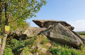 Hangenstein, © Mathias Pöcher Große Felsformation mit Baum und Schild im Vordergrund, blauer Himmel im Hintergrund.