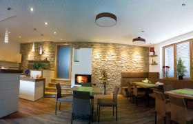 Verkostungsraum, © Fam. Wagner Ein moderner Verkostungsraum mit Holzmöbeln, Steinwand, Kamin und Pflanzen.