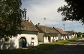 Kellergasse in Schöngrabern, © Rita Newman Reihe von Weinkellern in Schöngrabern, Österreich, bei sonnigem Wetter.