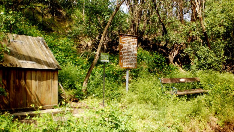 Romantischer Hohlweg Hasenecken, © Marktgemeinde Haugsdorf Holzhütte, Bank und Schilder in einem bewaldeten Gebiet.
