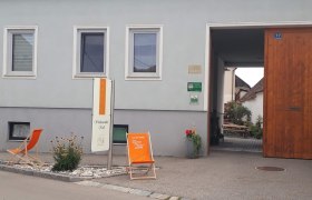 Weingut Krell, © Weingut Krell Eingang eines Weinguts mit Schild 'Krell', Liegestuhl und Pflanzen.