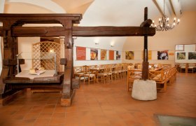 Althofheuriger, © Althof Retz Innenansicht eines traditionellen Heurigenlokals mit Holzmöbeln und einer alten Weinpresse.