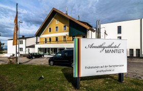 Amethysthotel Mantler, © Imre Antal Außenansicht des Amethysthotels Mantler mit Parkplatz und Schild.