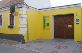 Buschenschank Wallig, © Fam. Wallig Gelbes Gebäude mit Holztor und Schild 'Wallig'.