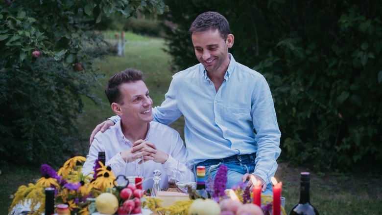 Die Winzer Gerald Wunderer und Matthias Lobner, © Stefan Jurecek Zwei Männer sitzen an einem Tisch im Freien, umgeben von Blumen und Kerzen.