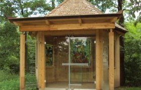 Kapelle am Köhlberg, © Marktgemeinde Ziersdorf Kleine Holzkapelle mit Glasfront und Kreuz auf dem Dach, umgeben von Bäumen.