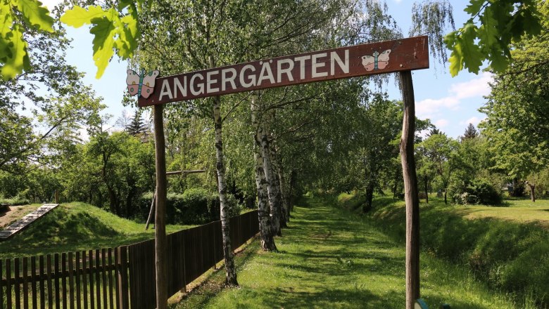 Eingang zu den Angergärten, © Wolfgang Gerzer Eingang zu den Angergärten mit Holzschild und Bäumen im Hintergrund.