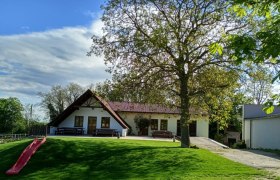 Gemütliche Heurigenterrasse am Weingut Puhr, © Viktoria Puhr Ein Weingut mit Terrasse, Bäumen und einer Rutsche im Vordergrund.