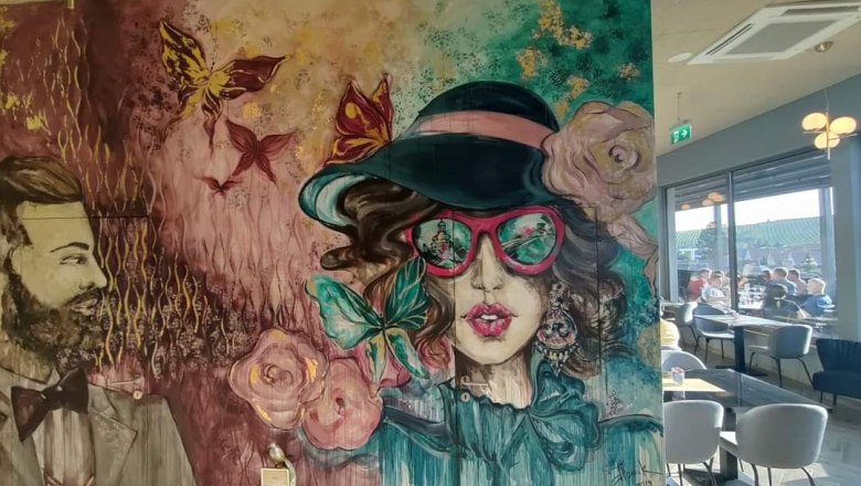 Rooftop Eingangsbereich, © Rebecca Freitag Wandgemälde mit stilisierten Porträts eines Mannes und einer Frau in einem Café.