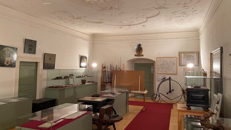 Heimat-Gewerbemuseum Pulkau, © Stadtgemeinde Pulkau Innenansicht eines Museumsraums mit Vitrinen, alten Karten und einem Hochrad.