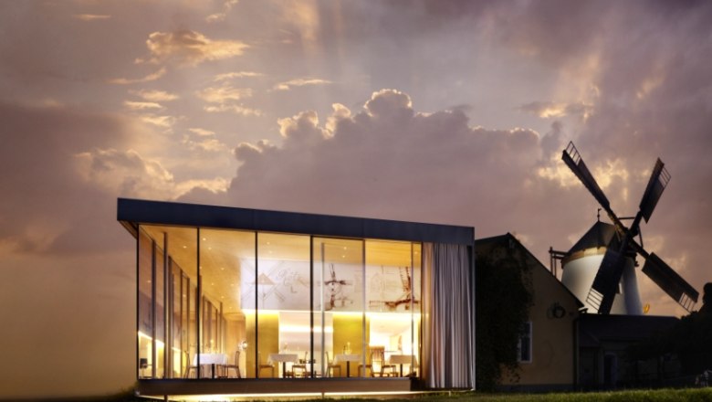 Windmühlheuriger Bergmann, © Alexander Schleissing Moderne Glasarchitektur neben einer traditionellen Windmühle bei Sonnenuntergang.