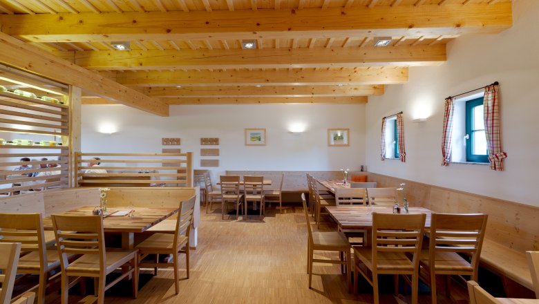 Weingut & Buschenschank Greilinger, © Greilinger Innenansicht eines gemütlichen Gastraums mit Holzmöbeln und Holzbalkendecke.