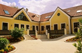 Gelbes Gebäude mit roten Ziegeldächern und Garten.