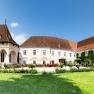 Panoramablick auf das Schloss Schrattenthal mit gepflegtem Garten und blühenden Rosen im Vordergrund.