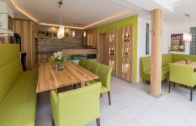 Moderner Verkostungsraum mit Holztischen und gr&uuml;nen Polsterm&ouml;beln.