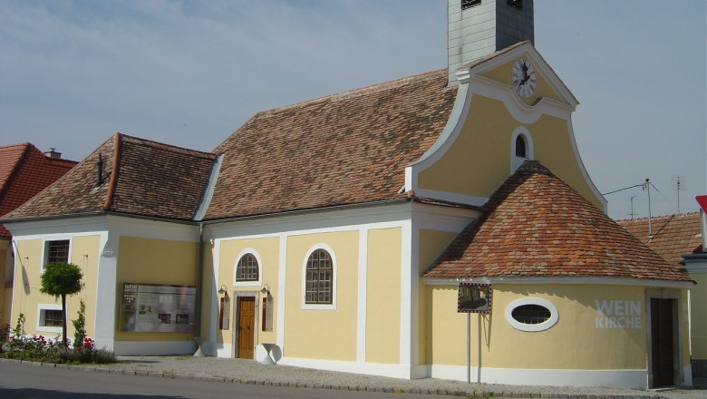 Gelbes Geb&auml;ude mit Turm und Uhr, bekannt als Weinkirche in Haugsdorf.