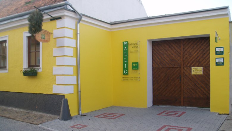 Gelbes Geb&auml;ude mit Holztor und Schild 'Wallig'.