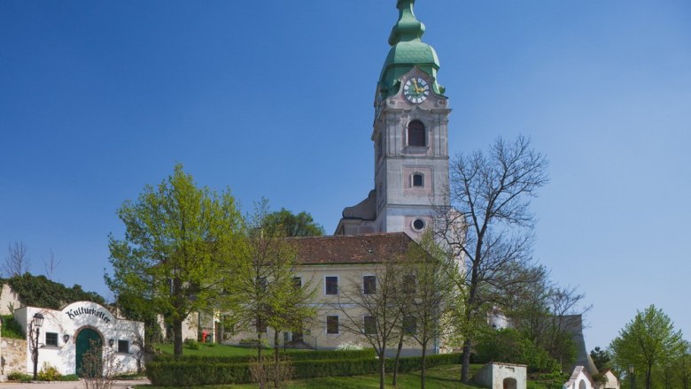 Kirche in Unterretzbach mit grünem Turm und umliegenden Gebäuden.