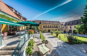Innenhof des Althof Retz mit Terrasse, Sonnenschirmen und Gartenm&ouml;beln.
