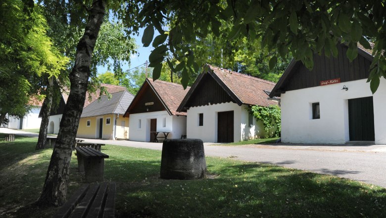 Eine malerische Kellergasse mit traditionellen Weinkellern und gr&uuml;ner Umgebung in Zellerndorf.