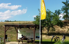 Radlerrastplatz mit Holztisch, zwei Fahrrädern und Infotafel im Weinviertel.