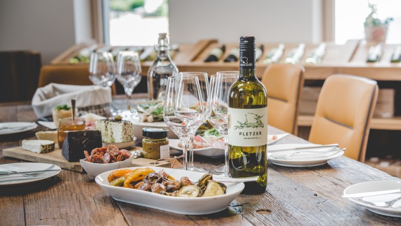 Ein gedeckter Tisch mit Weinflasche, Gläsern und verschiedenen Speisen.