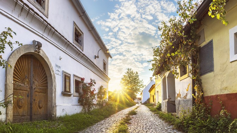 Kopfsteinpflasterstra&szlig;e in R&ouml;schitz mit historischen Geb&auml;uden und Sonnenuntergang.