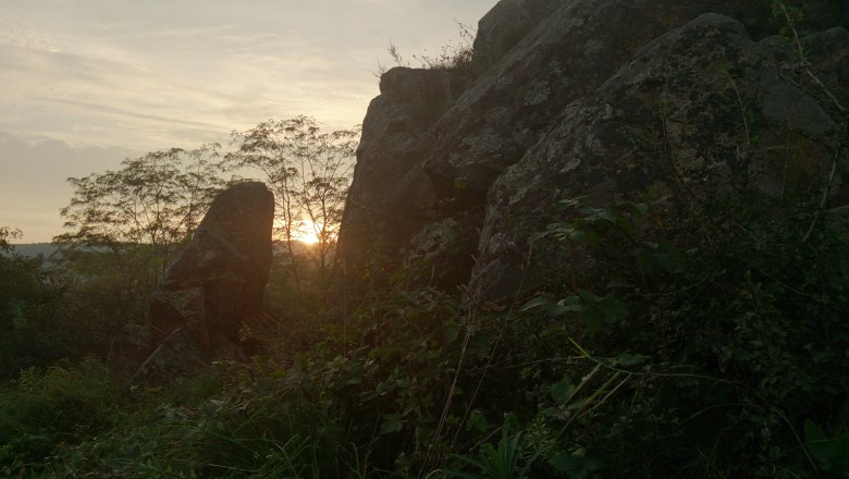Sonnenuntergang hinter gro&szlig;en Felsen und B&auml;umen in einer nat&uuml;rlichen Umgebung.