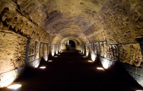 Ein beleuchteter, gewölbter Tunnel mit kunstvollen Reliefs an den Wänden.