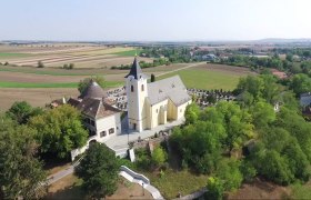 Luftaufnahme der Pfarrkirche Nappersdorf umgeben von Feldern und Bäumen.