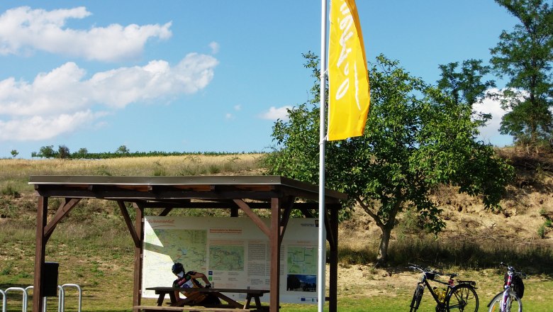 Radlerrastplatz mit Holztisch, zwei Fahrrädern und Infotafel im Weinviertel.