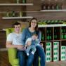 Ein Paar mit einem Baby sitzt auf einem grünen Sessel in einem Weingut.