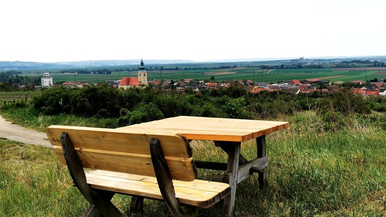Holzbank mit Tisch auf einem Hügel mit Blick auf Röschitz und umliegende Landschaft.