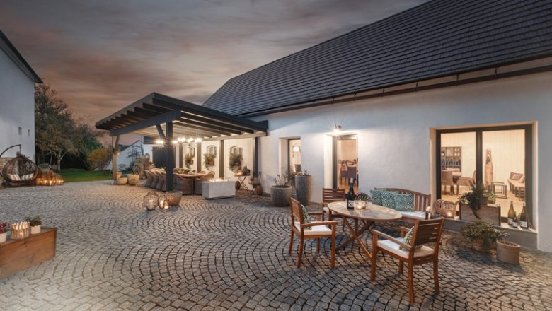 Gepflasterter Innenhof mit Tischen und St&uuml;hlen, umgeben von Geb&auml;uden bei Abendd&auml;mmerung.