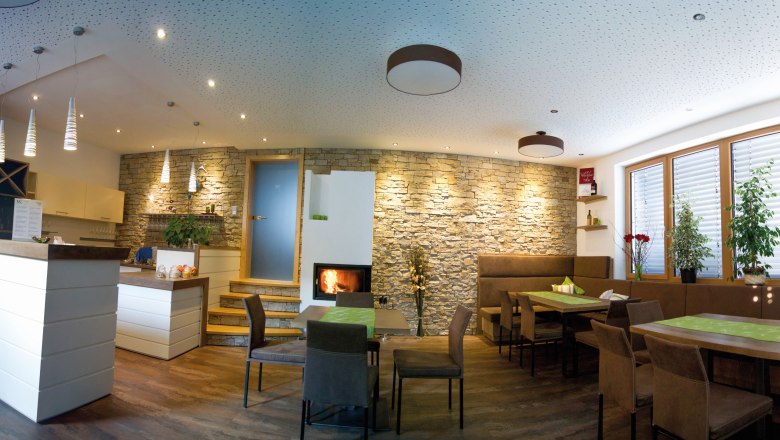Ein moderner Verkostungsraum mit Holzm&ouml;beln, Steinwand, Kamin und Pflanzen.