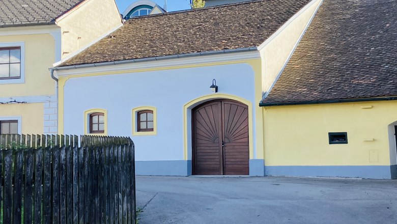Gelbes Geb&auml;ude mit Holztor und Schindeldach in Deinzendorf, Weinviertel.