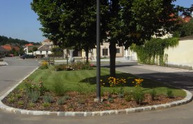 Ein gepflegtes Blumenbeet mit gelben Blumen und B&auml;umen in einer ruhigen Wohnstra&szlig;e.
