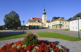 Hauptplatz in Sitzendorf mit Kirche und Blumenbeet.