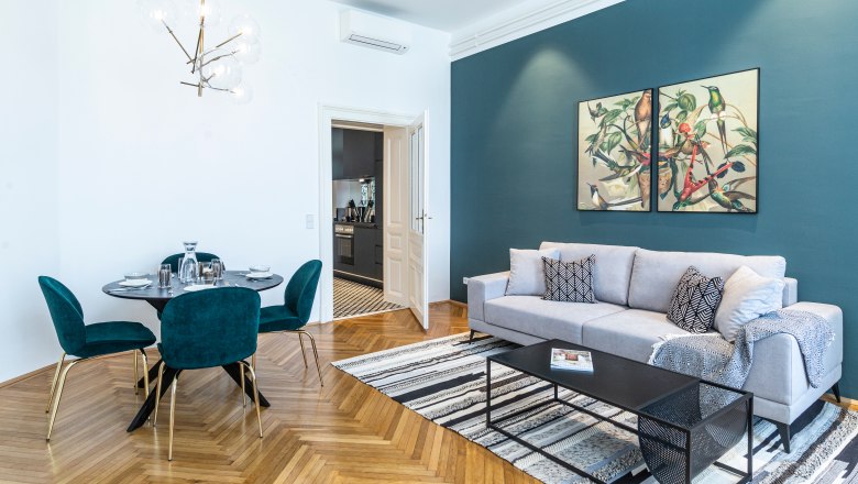 Modernes Wohnzimmer mit grauem Sofa, Esstisch und Kunst an der Wand.