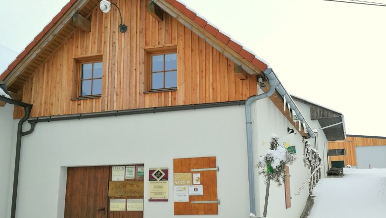 Ein traditionelles Gebäude mit Holzverkleidung und Schildern an der Wand, umgeben von Schnee.