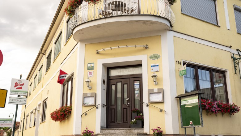 Gelbes Wirtshaus mit Blumen und Schildern, darunter "Stiegl" und "Retzerlandhof".