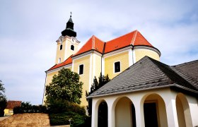 Pfarrkirche St. Nikolaus in R&ouml;schitz mit gelber Fassade und rotem Dach.