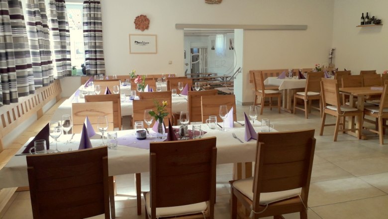 Innenansicht eines gem&uuml;tlichen Heurigenlokals mit gedeckten Tischen und Holzm&ouml;beln.